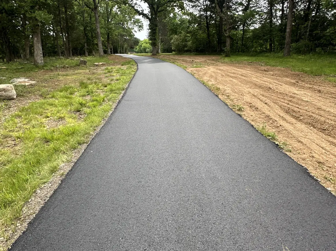 Roller compacting fresh hot mix asphalt on a long driveway, asphalt driveway paving