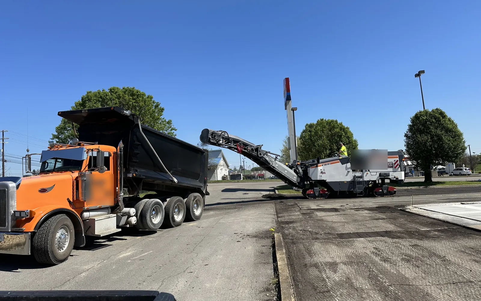 Full size milling machine and dump truck on a parking lot, asphalt milling
