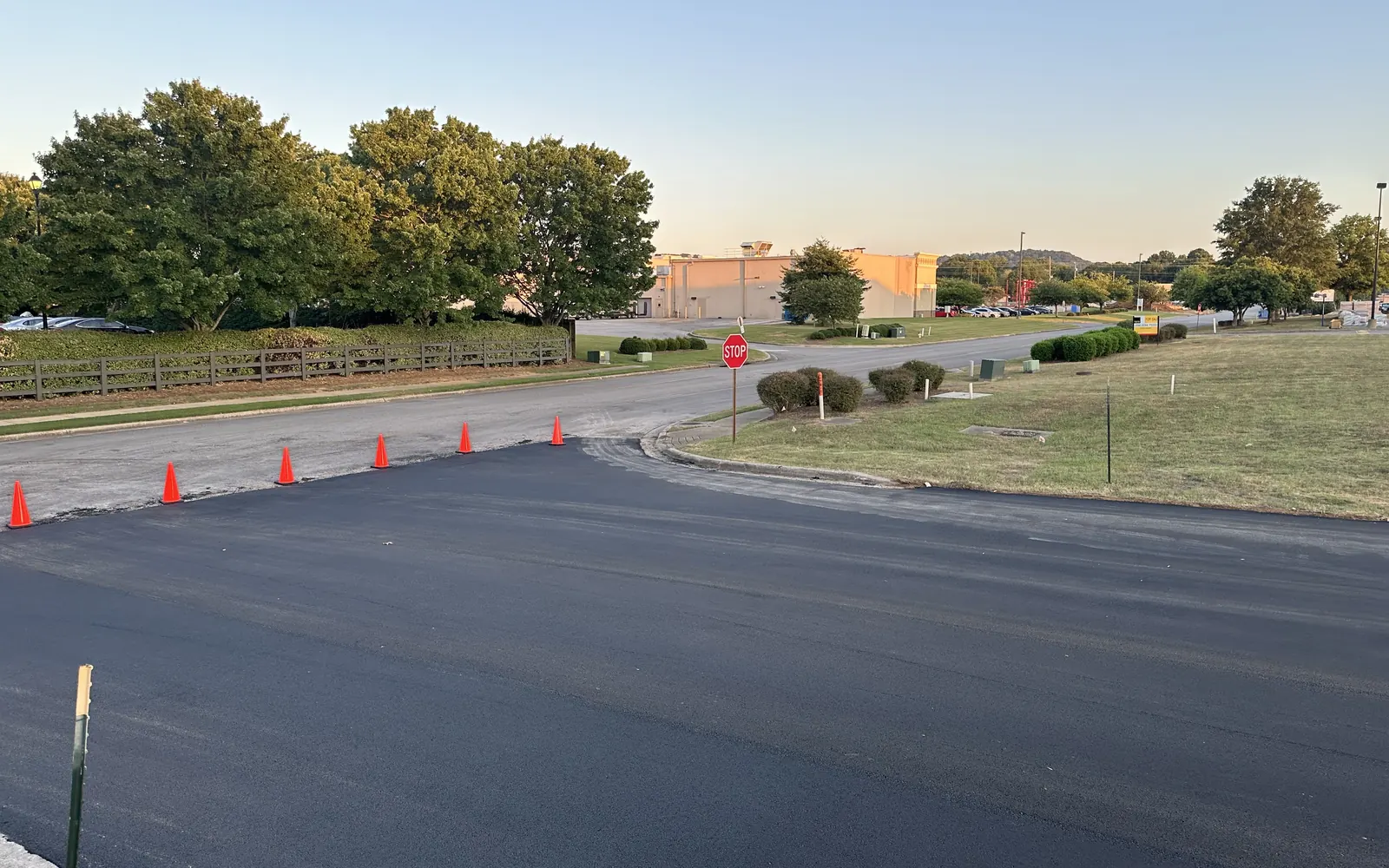 Freshly resurfaced parking lot corner with cones at the entrance, asphalt resurfacing