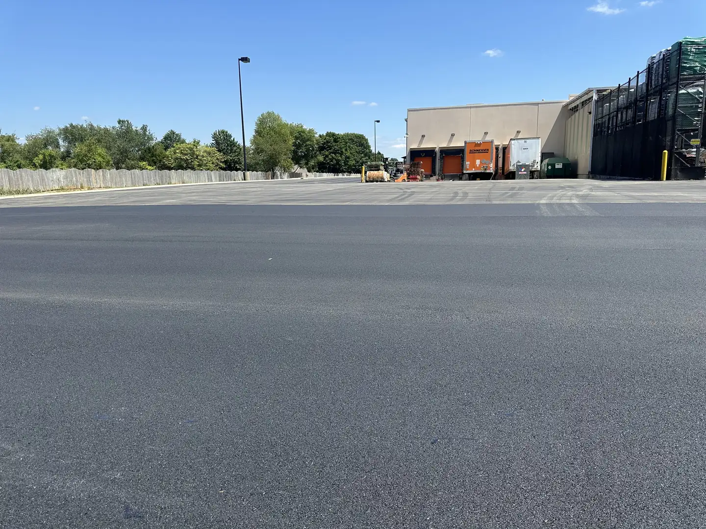 Resurfaced truck yard with fresh asphalt beside loading docks, asphalt resurfacing