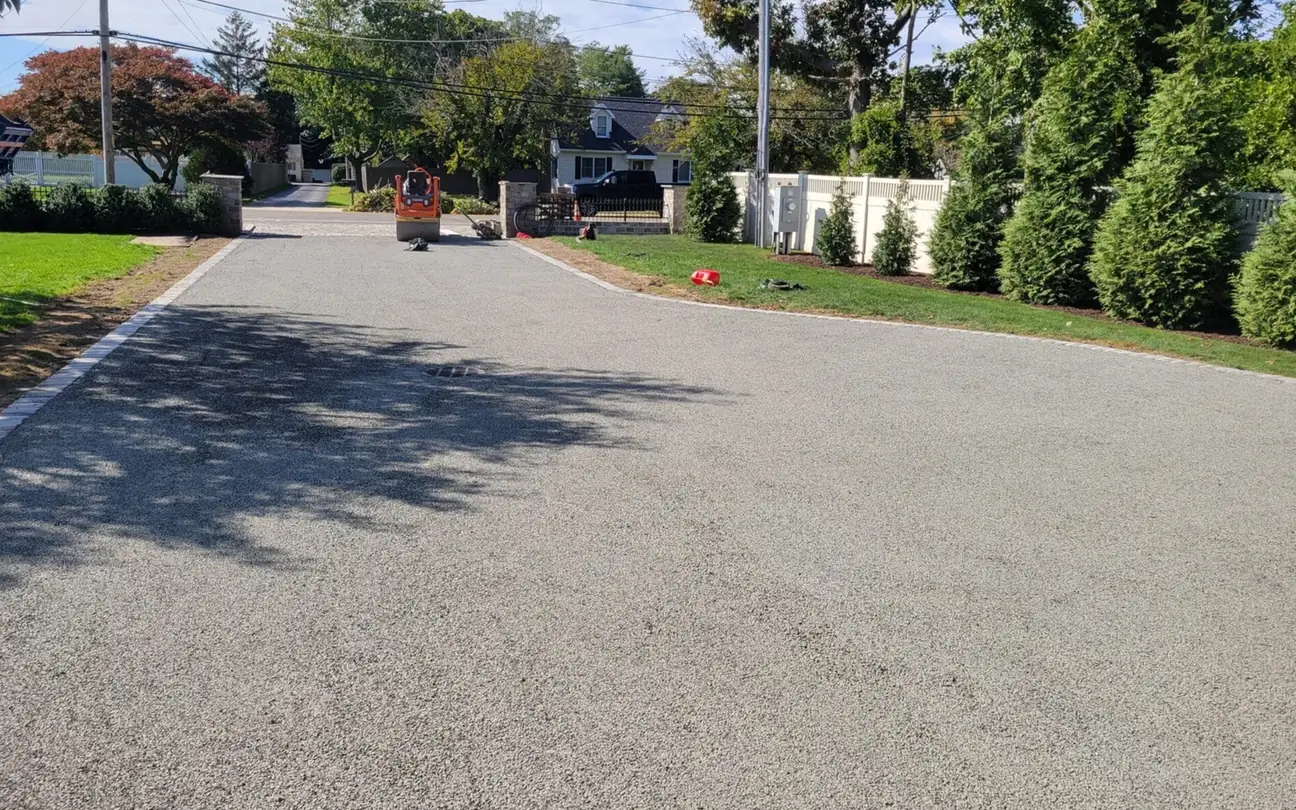Chip seal driveway with a roller working at the far end, chip seal