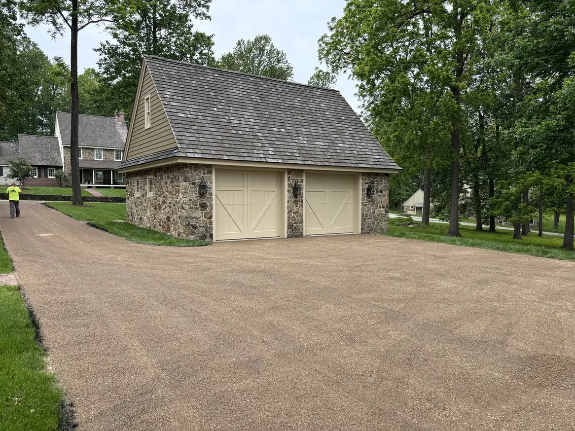 Tar and chip driveway in front of a stone garage, chip seal