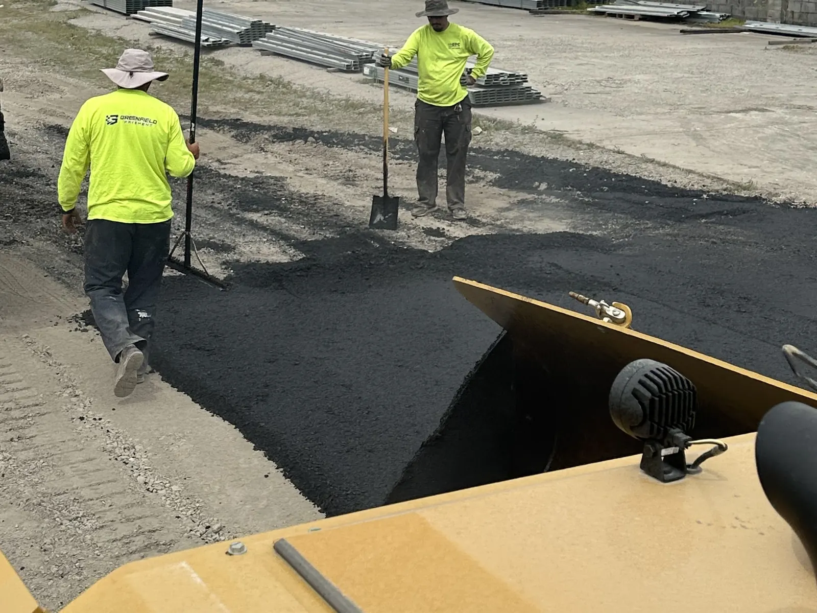 Crew raking hot mix asphalt behind the paver on a parking lot, parking lot paving