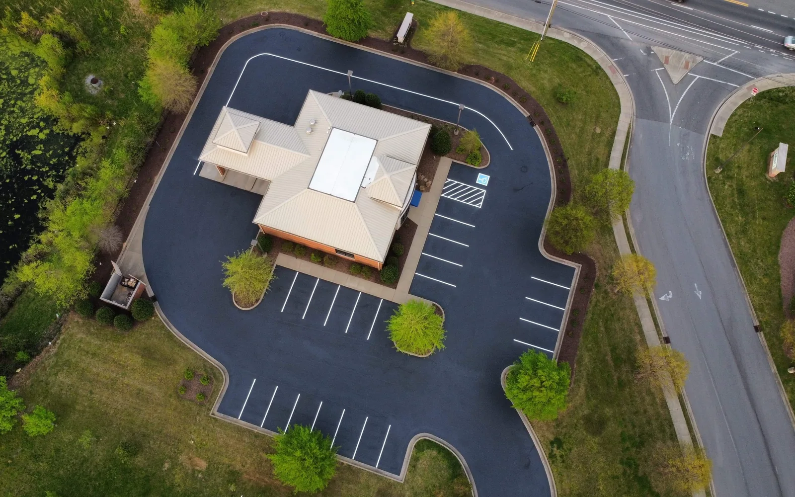 Finished parking lot with fresh white striping around an office building seen from above, parking lot paving