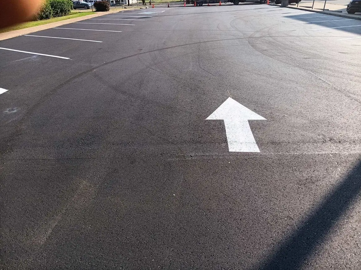 White directional arrow painted on fresh asphalt, parking lot striping